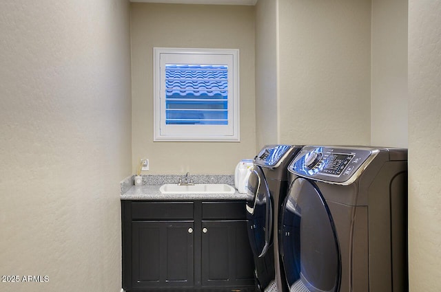 laundry area featuring a sink, cabinet space, a textured wall, and washer and dryer