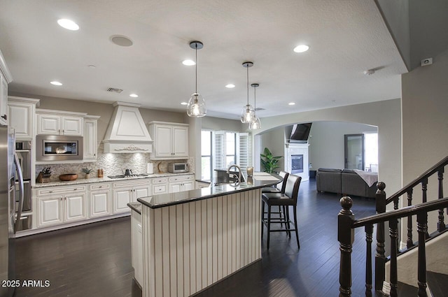 18515 N 97th Way, Scottsdale, AZ 85255 - kitchen with custom range hood, appliances with stainless steel finishes, arched walkways, a sink, and tasteful backsplash