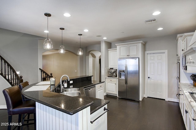 18515 N 97th Way, Scottsdale, AZ 85255 - kitchen featuring stainless steel appliances, a sink, arched walkways, white cabinets, and a large island