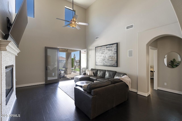 18515 N 97th Way, Scottsdale, AZ 85255 - living room featuring a ceiling fan, dark wood finished floors, arched walkways, a fireplace, and a high ceiling