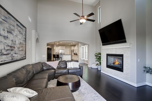 18515 N 97th Way, Scottsdale, AZ 85255 - living area with dark wood-style flooring, ceiling fan, arched walkways, a high ceiling, and a fireplace
