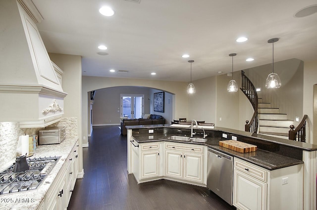 kitchen with arched walkways, a sink, open floor plan, stainless steel appliances, and dark wood-type flooring