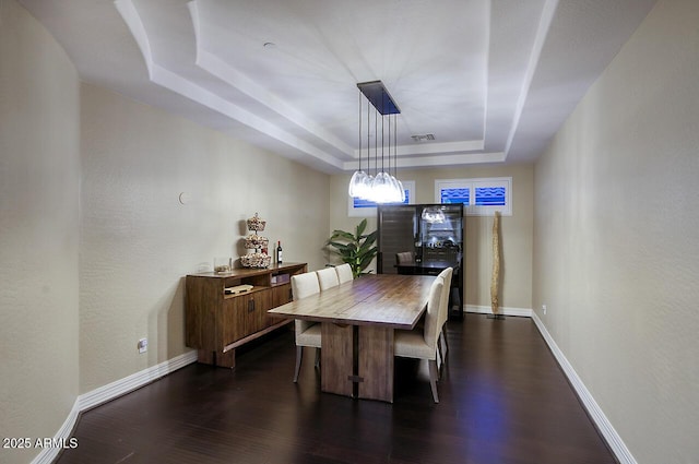 dining space with a raised ceiling, baseboards, dark wood-style floors, and visible vents