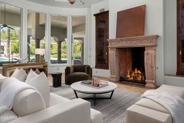 living room featuring a high end fireplace, ceiling fan, and light hardwood / wood-style floors