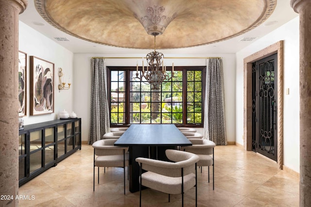 dining area featuring a raised ceiling, ornate columns, and an inviting chandelier