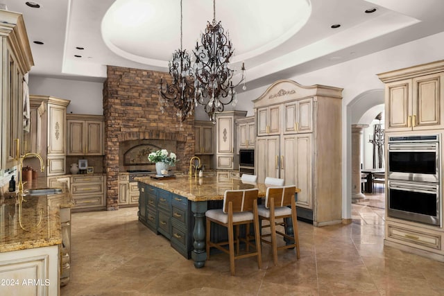 kitchen featuring a center island with sink, a raised ceiling, and sink