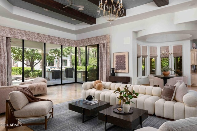 living room with ceiling fan with notable chandelier, beamed ceiling, and a high ceiling