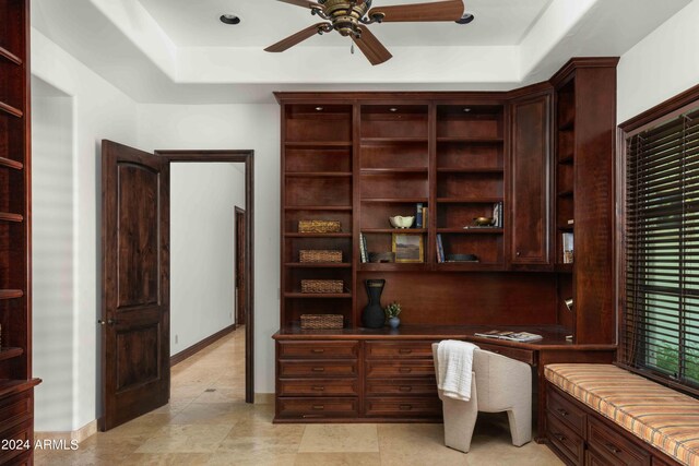 office space featuring a raised ceiling and ceiling fan