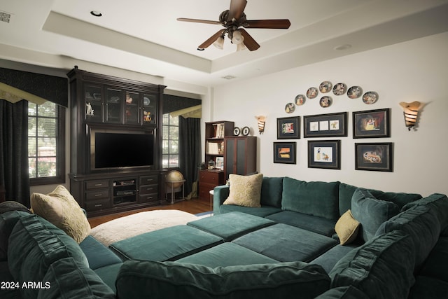 living room with a raised ceiling, ceiling fan, and hardwood / wood-style floors