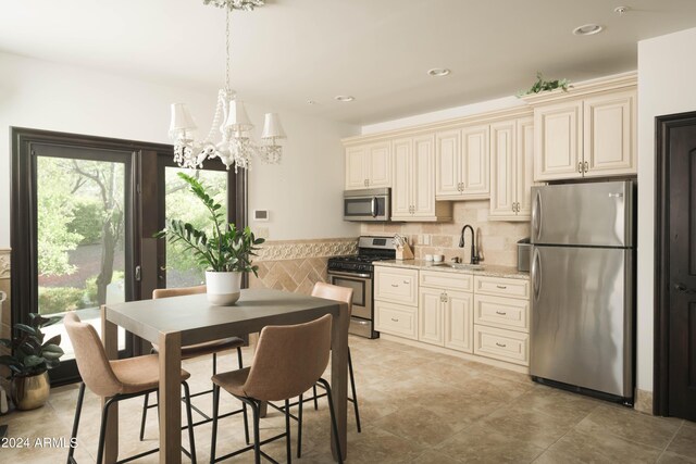 kitchen with cream cabinetry, appliances with stainless steel finishes, plenty of natural light, and a chandelier