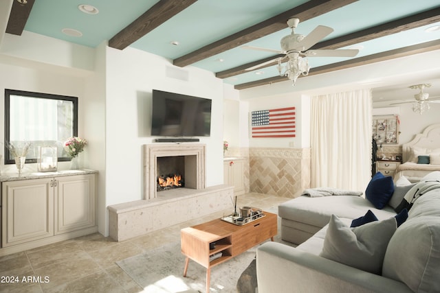 living room with a premium fireplace, ceiling fan, beamed ceiling, and tile walls