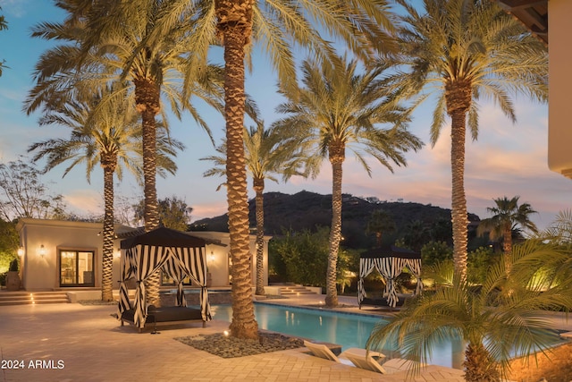 pool at dusk featuring a patio and a gazebo