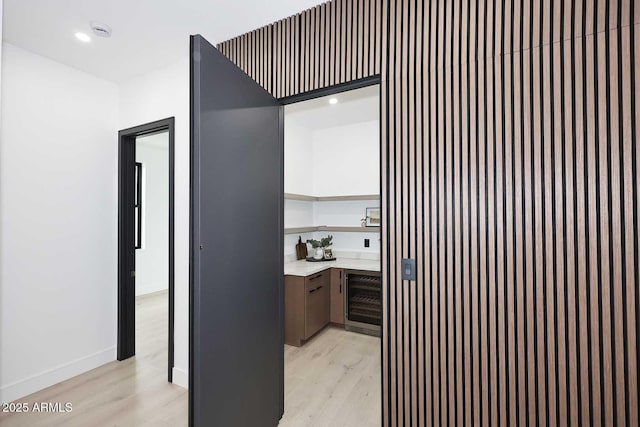 hallway with wine cooler, light wood-style flooring, baseboards, and recessed lighting