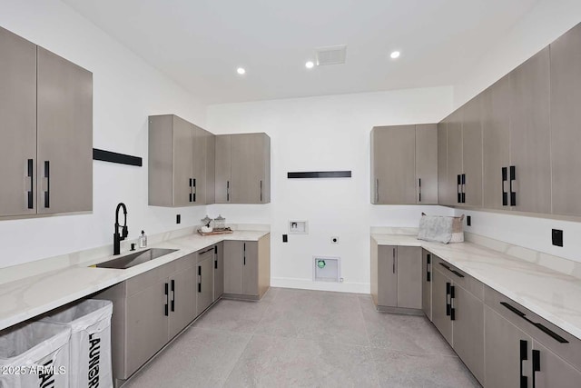 kitchen with modern cabinets, a sink, gray cabinetry, and light stone countertops