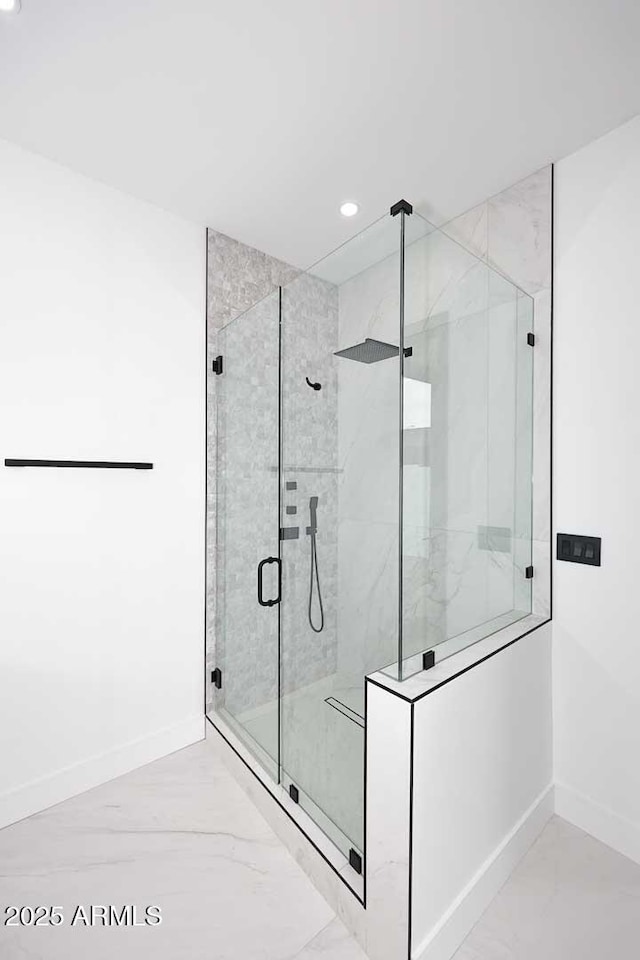 bathroom featuring marble finish floor, baseboards, and a stall shower