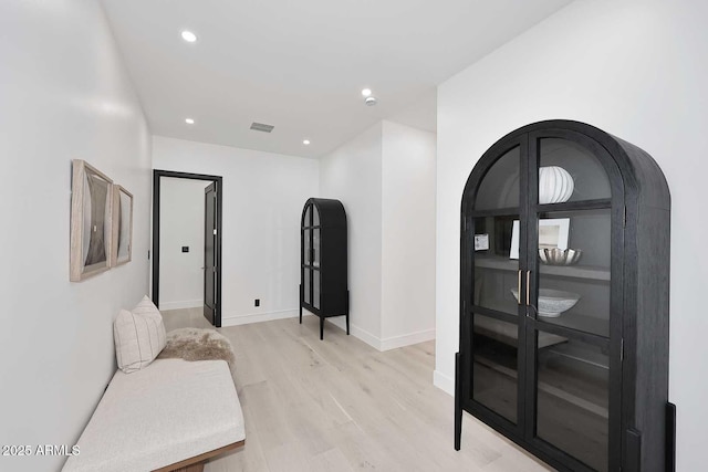 sitting room featuring light wood-style floors, visible vents, baseboards, and recessed lighting