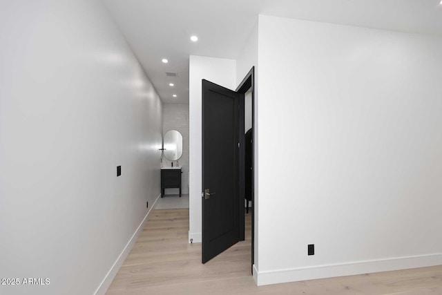 hall featuring light wood-style flooring, baseboards, and recessed lighting