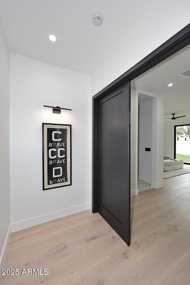 corridor featuring light wood-style flooring, visible vents, and baseboards