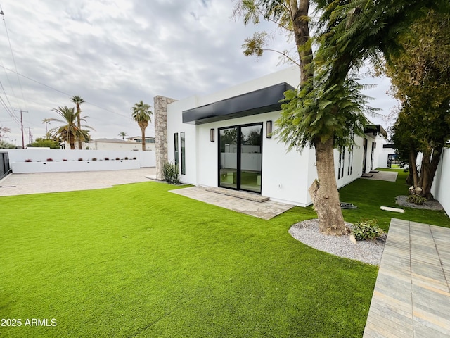 back of property with a yard, fence, and stucco siding