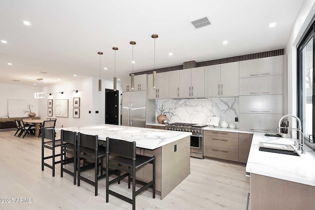 kitchen featuring high quality appliances, a kitchen island, light stone countertops, a kitchen bar, and pendant lighting