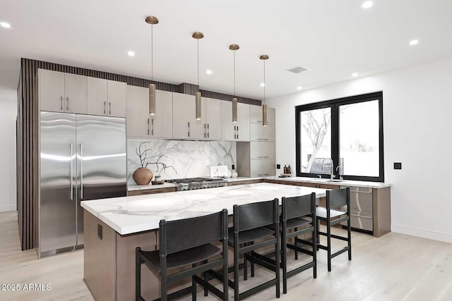 kitchen with a center island, hanging light fixtures, light stone countertops, stainless steel appliances, and backsplash