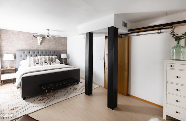 bedroom featuring light wood-type flooring and brick wall