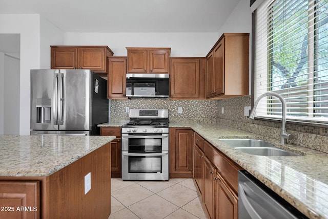 8710 N 182nd Ave, Waddell, AZ 85355 - kitchen featuring tasteful backsplash, light stone countertops, brown cabinets, a sink, and stainless steel appliances