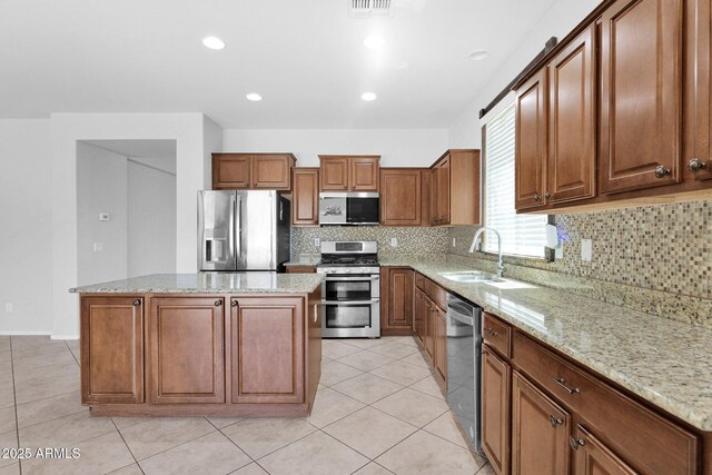 8710 N 182nd Ave, Waddell, AZ 85355 - kitchen featuring a center island, brown cabinets, tasteful backsplash, a sink, and stainless steel appliances