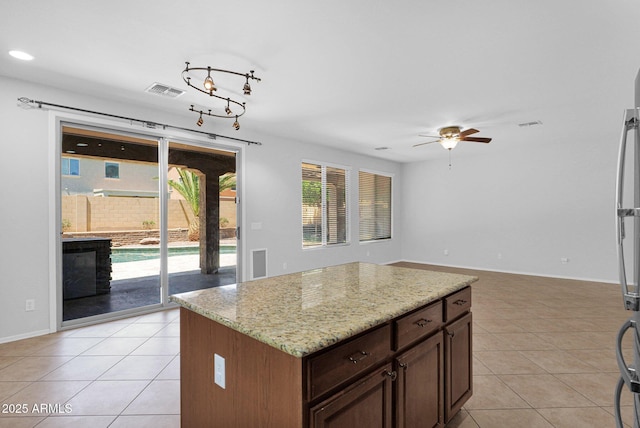 8710 N 182nd Ave, Waddell, AZ 85355 - kitchen featuring visible vents, light tile patterned flooring, open floor plan, ceiling fan, and light stone counters