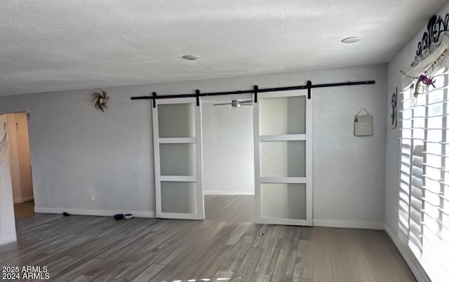 18828 N 17th Dr, Phoenix, AZ 85027 - unfurnished bedroom featuring a barn door, a textured ceiling, and wood finished floors