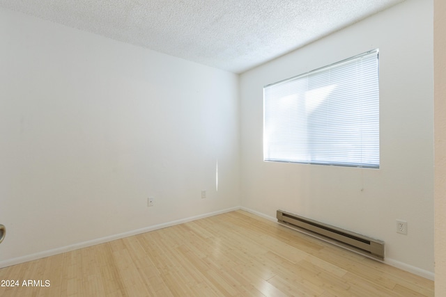 unfurnished room with light hardwood / wood-style floors, a textured ceiling, and a baseboard heating unit