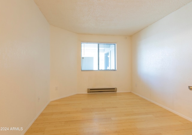 unfurnished room featuring baseboard heating, light hardwood / wood-style flooring, and a textured ceiling