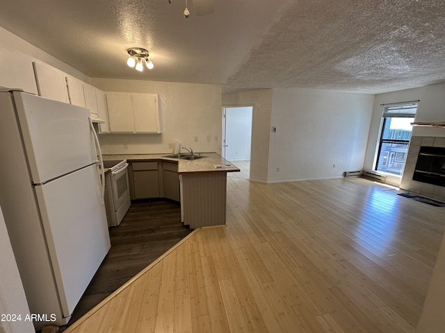 kitchen with kitchen peninsula, white appliances, sink, a fireplace, and dark hardwood / wood-style floors