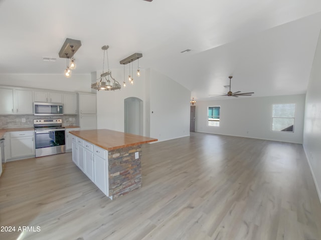 kitchen with appliances with stainless steel finishes, decorative light fixtures, a center island, white cabinets, and light wood-type flooring