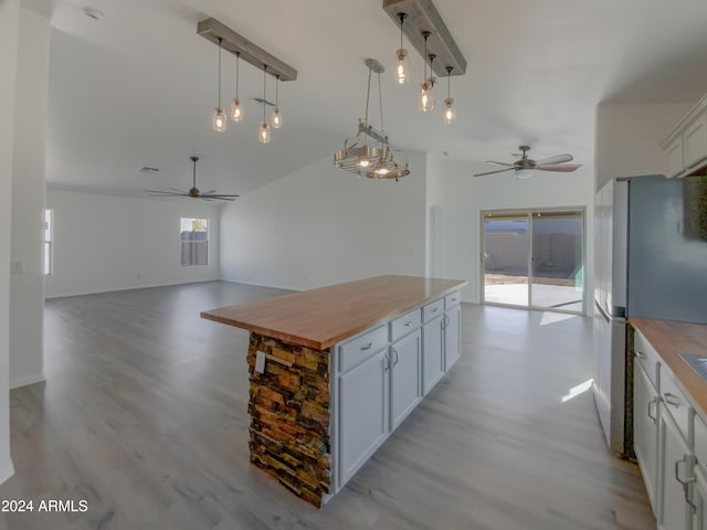 kitchen with stainless steel fridge, wood counters, decorative light fixtures, and a center island