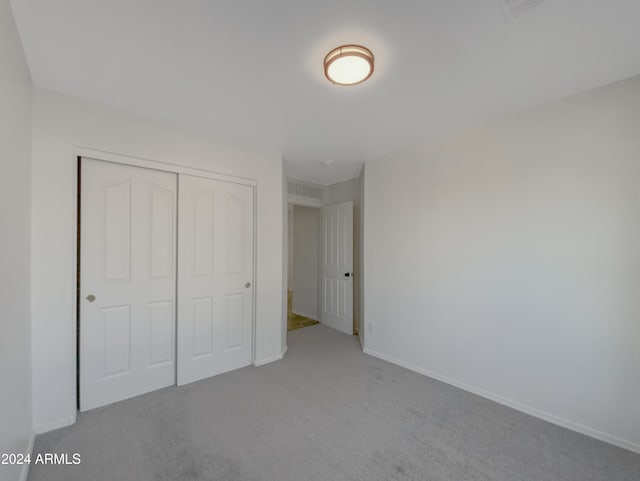 unfurnished bedroom featuring light colored carpet and a closet