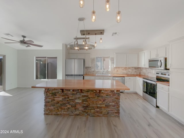 kitchen with light wood-type flooring, white cabinetry, appliances with stainless steel finishes, hanging light fixtures, and a center island