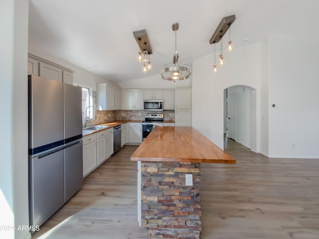 kitchen with wooden counters, a kitchen island, appliances with stainless steel finishes, vaulted ceiling, and light hardwood / wood-style flooring