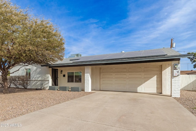 ranch-style house with a garage and solar panels