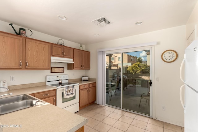 kitchen with white appliances, visible vents, light countertops, under cabinet range hood, and a sink