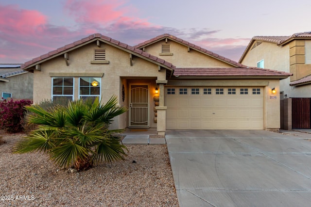 view of front of house featuring driveway, an attached garage, a tile roof, and stucco siding