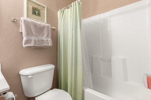 bathroom with toilet, shower / bath combination with curtain, and a textured wall