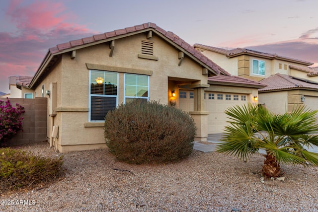 view of front of home with an attached garage, fence, and stucco siding