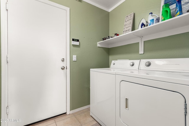 clothes washing area with washing machine and dryer, laundry area, crown molding, and light tile patterned floors