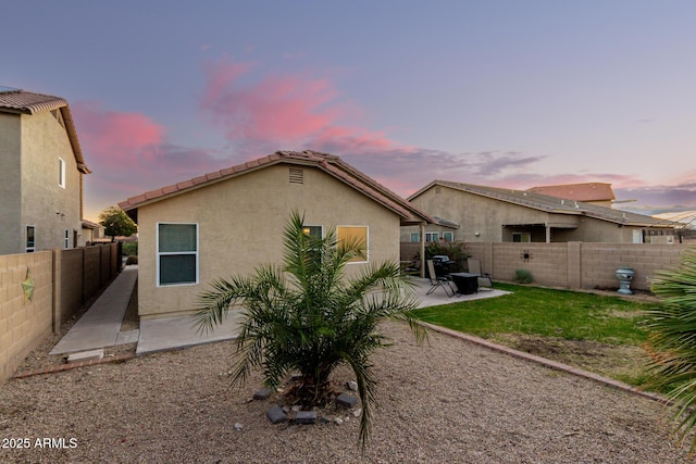 back of property with a fenced backyard, a patio, and stucco siding