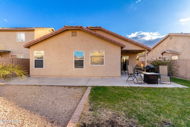 rear view of property featuring a patio, a lawn, fence, and stucco siding