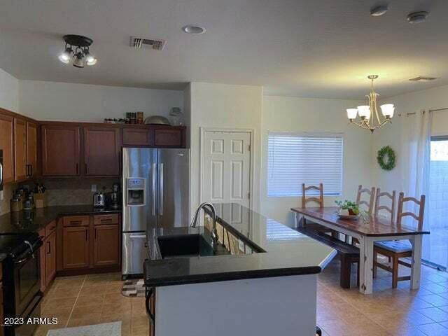 kitchen featuring light tile patterned floors, stove, stainless steel fridge with ice dispenser, hanging light fixtures, and a chandelier