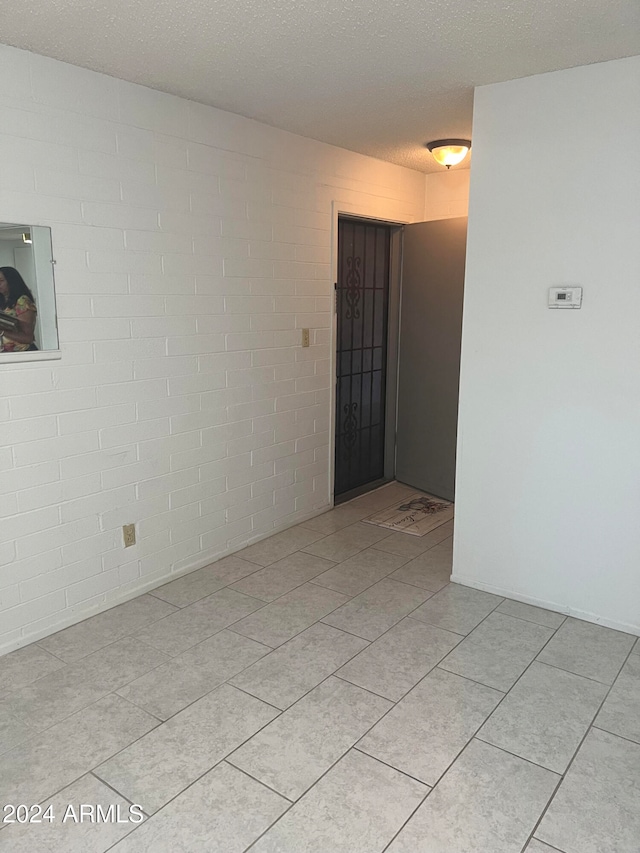 spare room featuring a textured ceiling and light tile patterned floors