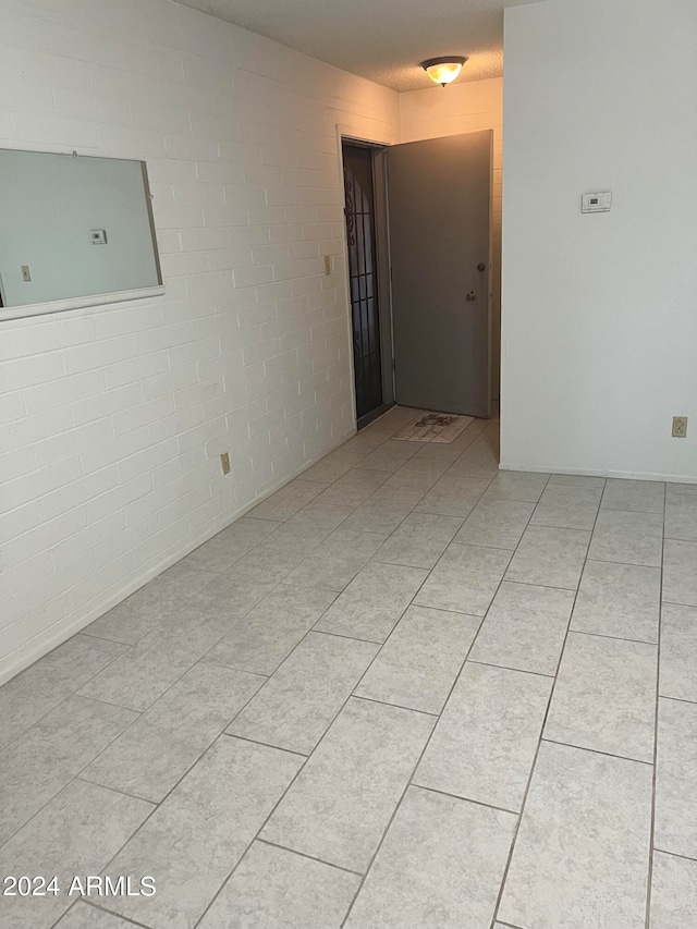 empty room with brick wall and light tile patterned floors