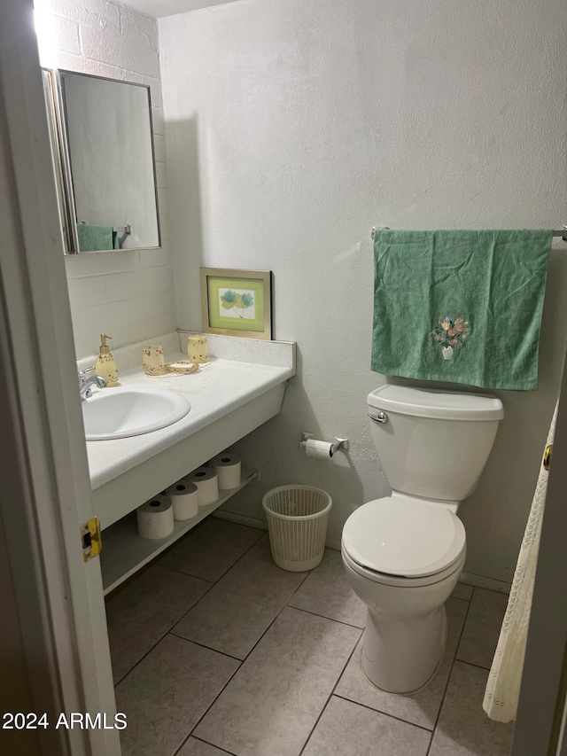 bathroom with toilet, tile patterned floors, and sink